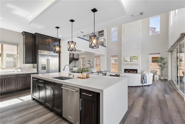 2890 Reverence Heights Ln, Las Vegas, NV 89138 - kitchen with appliances with stainless steel finishes, a sink, a fireplace, light countertops, and a towering ceiling