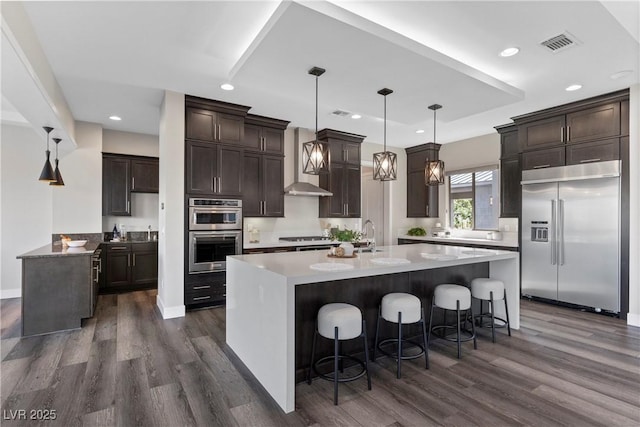 2890 Reverence Heights Ln, Las Vegas, NV 89138 - kitchen with appliances with stainless steel finishes, dark wood-style flooring, dark brown cabinetry, a center island with sink, and recessed lighting