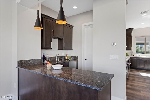 2890 Reverence Heights Ln, Las Vegas, NV 89138 - kitchen with dark brown cabinets, dark wood-style flooring, dark stone counters, a peninsula, and recessed lighting