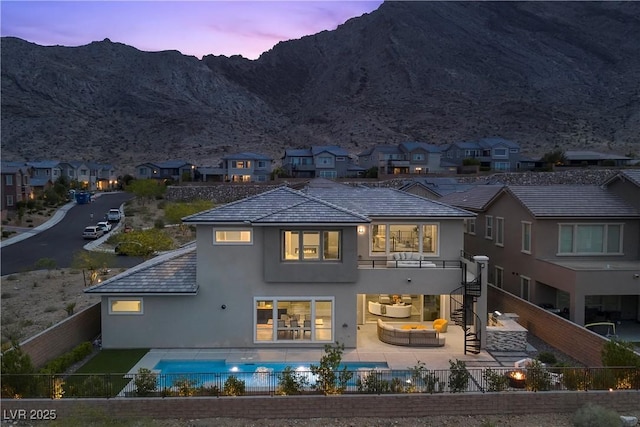 2890 Reverence Heights Ln, Las Vegas, NV 89138 - back of house at dusk with a fenced backyard, stucco siding, an outdoor living space, and a residential view