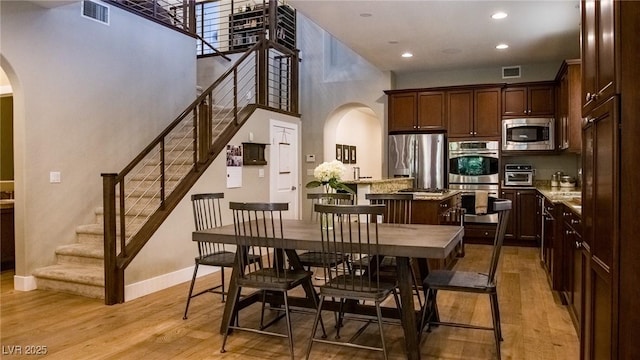 11731 Longworth Rd, Las Vegas, NV 89135 - dining area with arched walkways, a towering ceiling, stairs, light wood-type flooring, and baseboards
