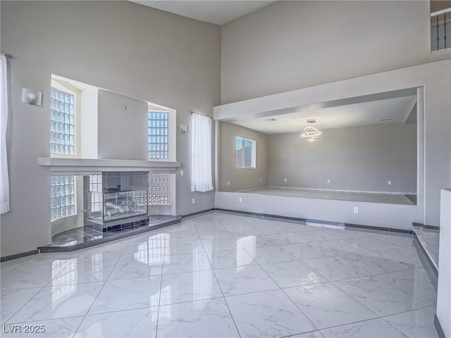 420 Dakar St, Henderson, NV 89015 - unfurnished living room featuring baseboards, marble finish flooring, a towering ceiling, and a fireplace