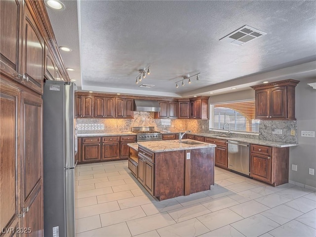 420 Dakar St, Henderson, NV 89015 - kitchen featuring stainless steel appliances, wall chimney exhaust hood, a textured ceiling, a kitchen island with sink, and a sink