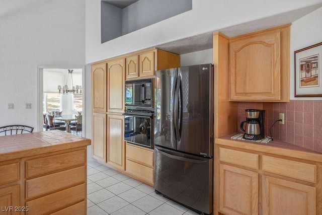 8236 Round Hills Cir, Las Vegas, NV 89113 - kitchen with black appliances, tile countertops, light brown cabinetry, light tile patterned floors, and a towering ceiling