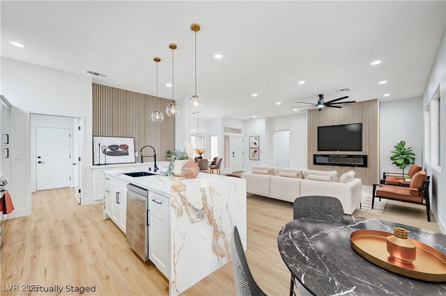 2353 Lauren Dr, Las Vegas, NV 89134 - kitchen featuring stainless steel dishwasher, light wood-type flooring, recessed lighting, a center island with sink, and light stone counters