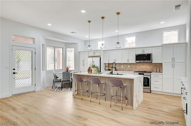 2353 Lauren Dr, Las Vegas, NV 89134 - kitchen with appliances with stainless steel finishes, light wood-style flooring, backsplash, a center island with sink, and recessed lighting