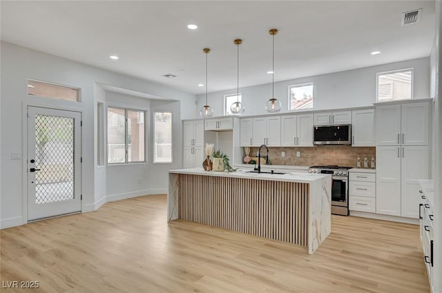 2353 Lauren Dr, Las Vegas, NV 89134 - kitchen featuring stainless steel appliances, light wood-style floors, decorative backsplash, light countertops, and a center island with sink