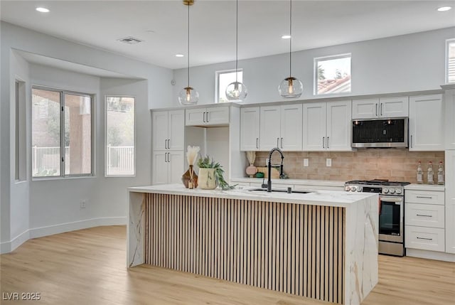 2353 Lauren Dr, Las Vegas, NV 89134 - kitchen featuring stainless steel appliances, light wood-style flooring, backsplash, a center island with sink, and pendant lighting