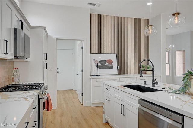 2353 Lauren Dr, Las Vegas, NV 89134 - kitchen featuring appliances with stainless steel finishes, tasteful backsplash, light wood finished floors, light stone counters, and pendant lighting