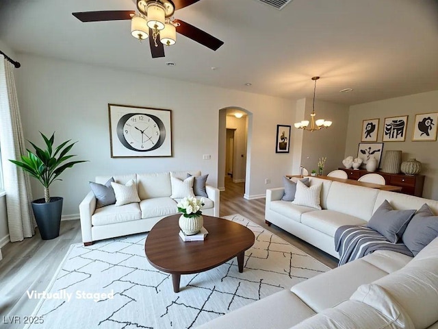 6313 Snap Ridge St Unit 201, North Las Vegas, NV 89081 - living area with arched walkways, a chandelier, a ceiling fan, light wood-style floors, and baseboards