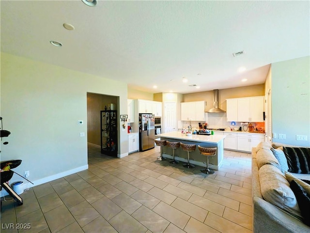 6021 Vivanco St, North Las Vegas, NV 89081 - kitchen featuring open floor plan, wall chimney range hood, stainless steel refrigerator with ice dispenser, a kitchen bar, and white cabinets