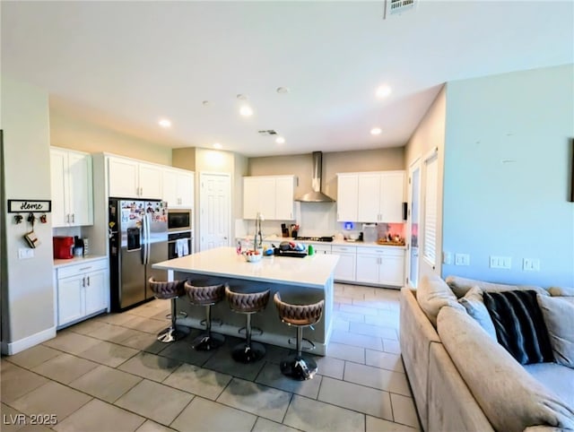 6021 Vivanco St, North Las Vegas, NV 89081 - kitchen featuring stainless steel appliances, wall chimney exhaust hood, open floor plan, a kitchen bar, and light countertops