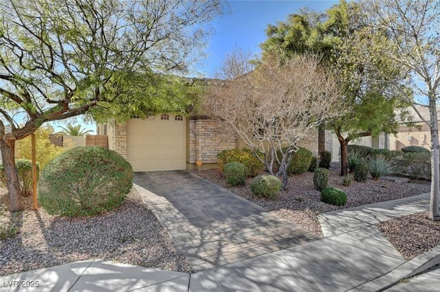 7331 Abundant Harvest Ave, Las Vegas, NV 89131 - obstructed view of property featuring a garage, driveway, stone siding, and stucco siding
