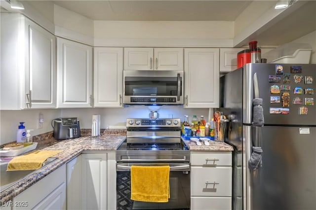 3930 University Center Dr Unit 706, Las Vegas, NV 89119 - kitchen featuring appliances with stainless steel finishes, white cabinets, a sink, and light stone countertops