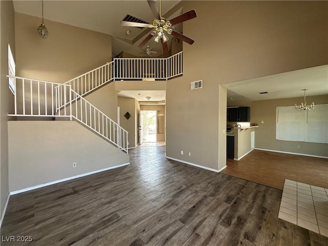 5128 Sandstone Dr, Las Vegas, NV 89142 - unfurnished living room featuring dark wood-type flooring, ceiling fan, a towering ceiling, stairway, and baseboards