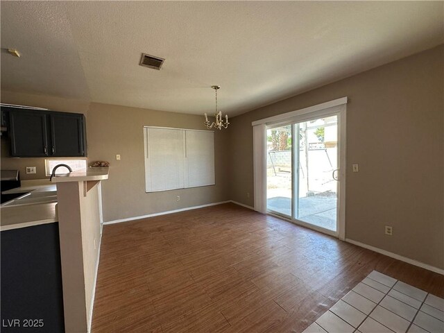 5128 Sandstone Dr, Las Vegas, NV 89142 - kitchen with a chandelier, light countertops, dark cabinets, wood finished floors, and baseboards