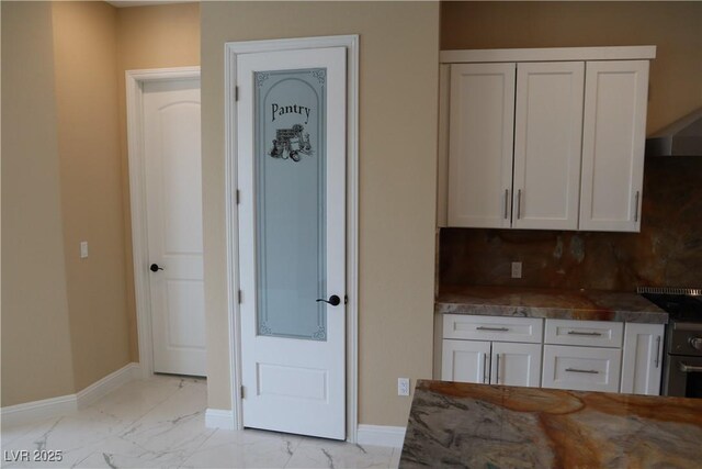 197 E Shelbourne Ave, Las Vegas, NV 89123 - kitchen with white cabinets, light marble finish flooring, baseboards, and backsplash