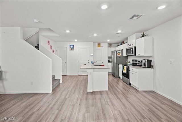 9929 Bumblebee Hills St, Las Vegas, NV 89141 - kitchen featuring stainless steel appliances, a sink, a center island with sink, light wood-style flooring, and white cabinets