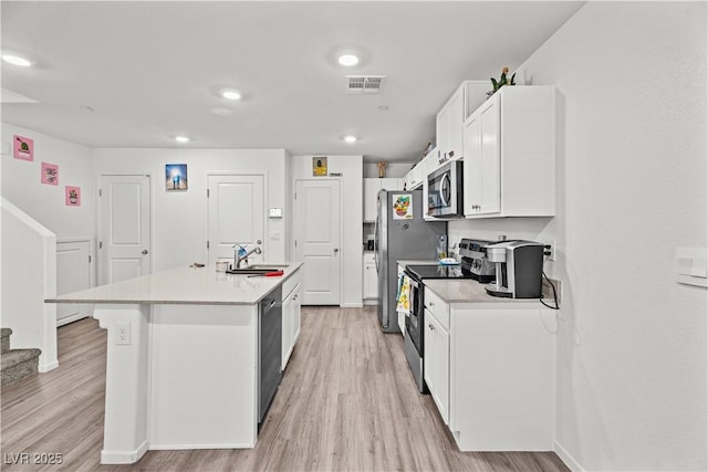 9929 Bumblebee Hills St, Las Vegas, NV 89141 - kitchen featuring stainless steel appliances, a sink, light wood-style flooring, white cabinets, and an island with sink