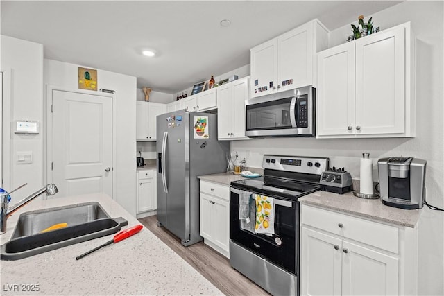 9929 Bumblebee Hills St, Las Vegas, NV 89141 - kitchen with stainless steel appliances, a sink, light wood-style flooring, white cabinets, and recessed lighting
