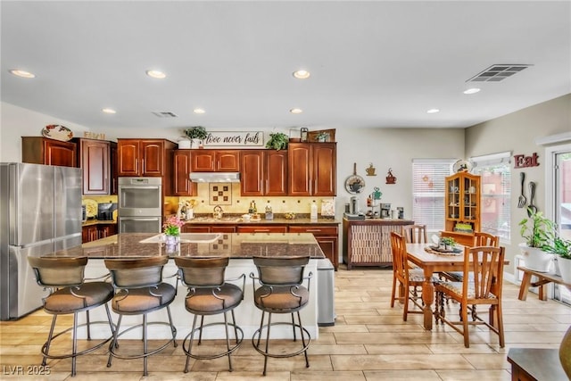 10420 Loma Portal Ave, Las Vegas, NV 89166 - kitchen featuring appliances with stainless steel finishes, under cabinet range hood, a breakfast bar, backsplash, and recessed lighting