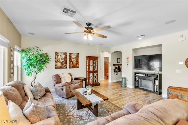 10420 Loma Portal Ave, Las Vegas, NV 89166 - living room featuring wood finished floors, arched walkways, a ceiling fan, a fireplace, and baseboards