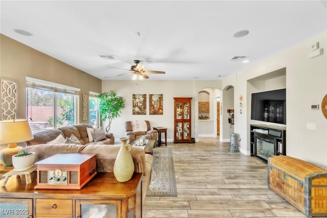 10420 Loma Portal Ave, Las Vegas, NV 89166 - living area with a ceiling fan, arched walkways, light wood-style floors, a glass covered fireplace, and baseboards