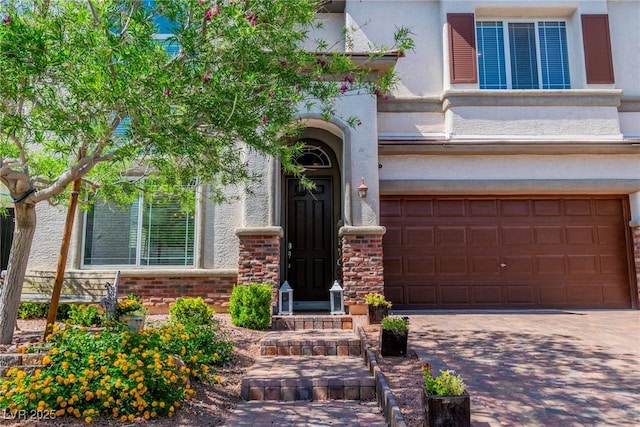 10420 Loma Portal Ave, Las Vegas, NV 89166 - doorway to property with a garage, stucco siding, decorative driveway, and brick siding