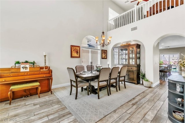 10420 Loma Portal Ave, Las Vegas, NV 89166 - dining area featuring arched walkways, light wood finished floors, baseboards, a chandelier, and a towering ceiling
