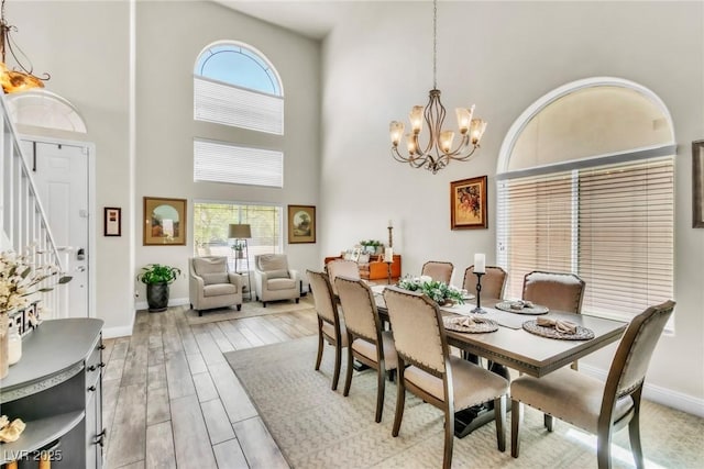 10420 Loma Portal Ave, Las Vegas, NV 89166 - dining area featuring a high ceiling, a chandelier, baseboards, stairway, and wood finished floors