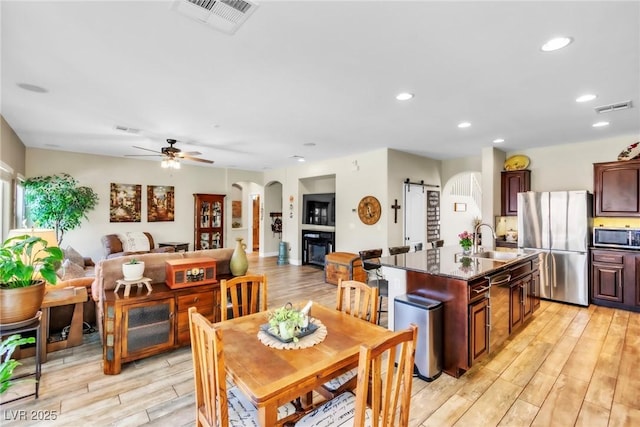 10420 Loma Portal Ave, Las Vegas, NV 89166 - dining room featuring a ceiling fan, light wood-style floors, recessed lighting, arched walkways, and a barn door