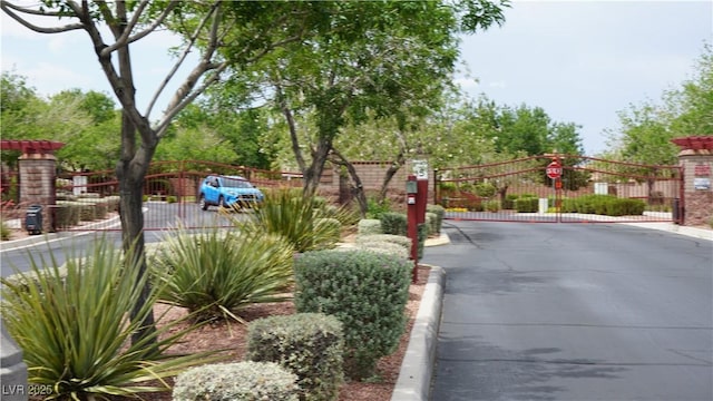 10420 Loma Portal Ave, Las Vegas, NV 89166 - view of asphalt road with a gate, a gated entry, traffic signs, and curbs