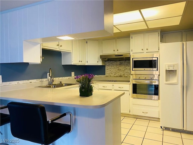 3766 Colonial Dr, Las Vegas, NV 89121 - kitchen with appliances with stainless steel finishes, a sink, under cabinet range hood, a peninsula, and light countertops