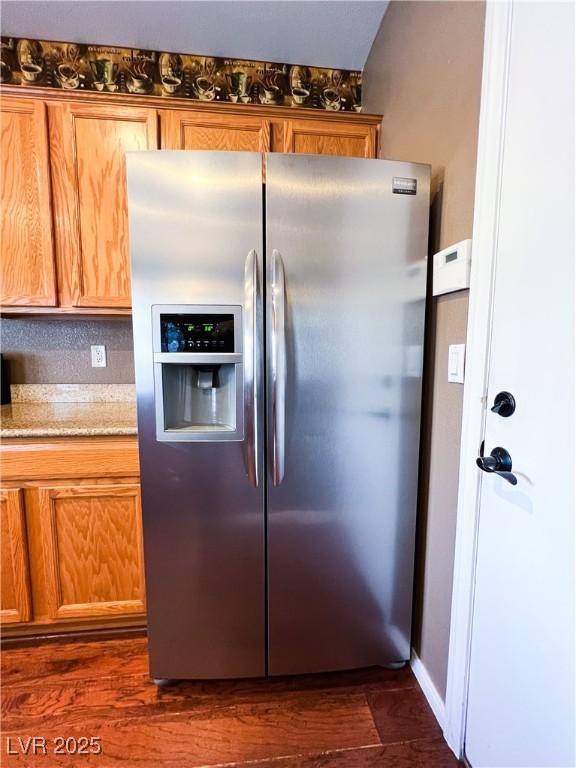 3412 Catherine Mermet Ave, North Las Vegas, NV 89081 - kitchen featuring stainless steel fridge, light stone counters, dark wood-type flooring, and brown cabinets