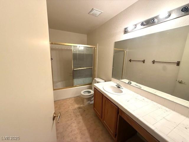 7570 W Flamingo Rd Unit 202, Las Vegas, NV 89147 - bathroom featuring vanity, toilet, and bath / shower combo with glass door