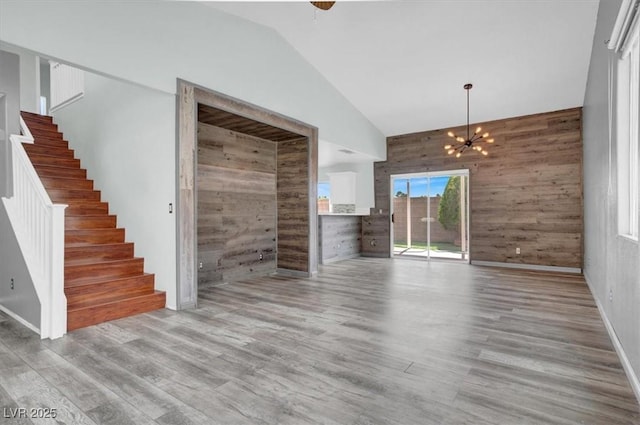 8389 Charlton Valley Ct, Las Vegas, NV 89123 - unfurnished living room with wood walls, lofted ceiling, stairway, a chandelier, and wood finished floors