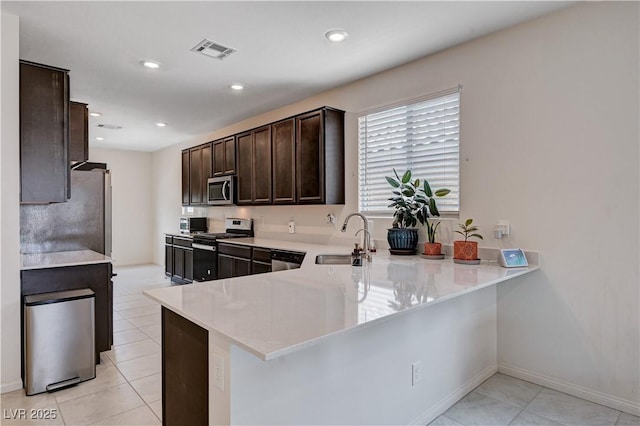 4293 Nopal Serrano Ave, Las Vegas, NV 89141 - kitchen with stainless steel appliances, a sink, dark brown cabinetry, light countertops, and a peninsula
