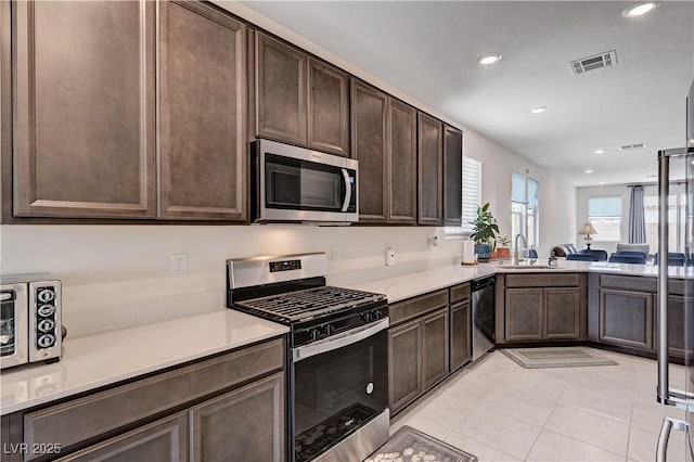 4293 Nopal Serrano Ave, Las Vegas, NV 89141 - kitchen with stainless steel appliances, dark brown cabinetry, light countertops, a sink, and light tile patterned floors
