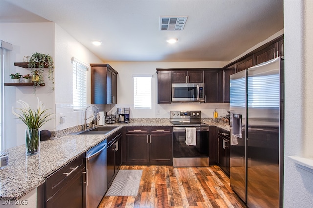 6819 Citron Mist Ct, North Las Vegas, NV 89086 - kitchen with appliances with stainless steel finishes, a sink, wood finished floors, dark brown cabinets, and light stone countertops
