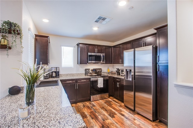 6819 Citron Mist Ct, North Las Vegas, NV 89086 - kitchen featuring appliances with stainless steel finishes, dark brown cabinets, a sink, light stone counters, and recessed lighting