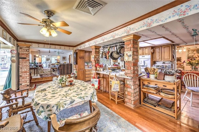 2045 S Tenaya Way, Las Vegas, NV 89117 - dining room featuring ornate columns, light wood-type flooring, ornamental molding, a ceiling fan, and a textured ceiling