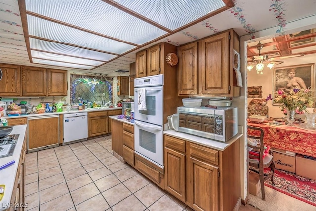 2045 S Tenaya Way, Las Vegas, NV 89117 - kitchen with white appliances, brown cabinetry, light countertops, a ceiling fan, and light tile patterned floors