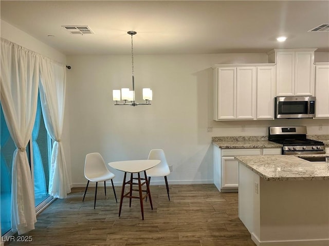 965 Nevada State Dr Unit 39102, Henderson, NV 89002 - kitchen with appliances with stainless steel finishes, wood finished floors, a chandelier, light stone counters, and white cabinets