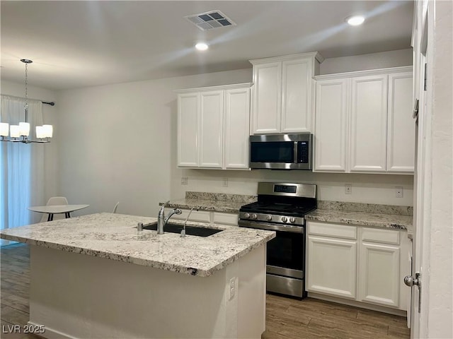 965 Nevada State Dr Unit 39102, Henderson, NV 89002 - kitchen with appliances with stainless steel finishes, a chandelier, wood finished floors, white cabinets, and decorative light fixtures
