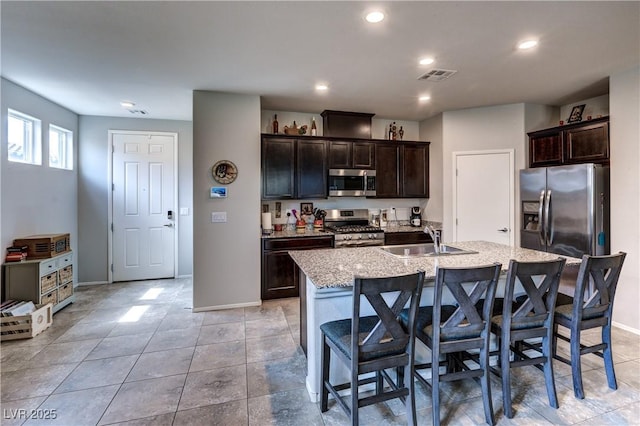 5854 Olivine Falls Ave, Las Vegas, NV 89130 - kitchen featuring stainless steel appliances, a sink, baseboards, a breakfast bar, and dark brown cabinets