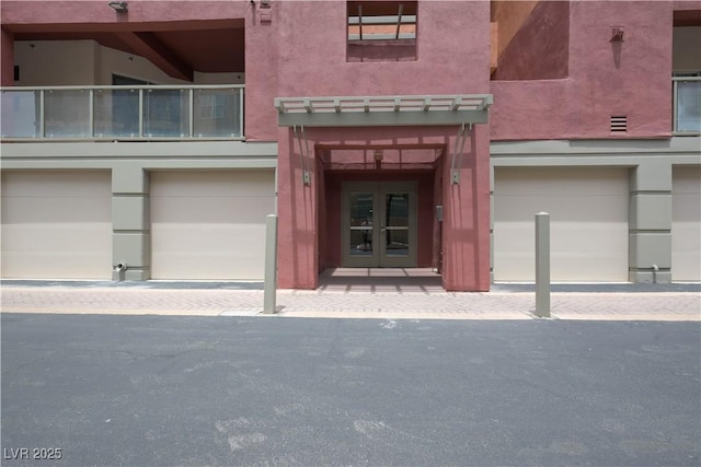 35 E Agate Ave Unit 208, Las Vegas, NV 89123 - view of exterior entry with french doors, a garage, driveway, a balcony, and stucco siding