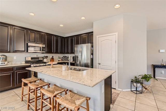 7761 Sagamore Bay Ct, Las Vegas, NV 89179 - kitchen featuring stainless steel appliances, a sink, light tile patterned floors, a kitchen bar, and recessed lighting