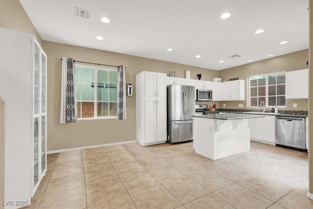 9869 Lime Tree St, Las Vegas, NV 89178 - kitchen featuring stainless steel appliances, a sink, white cabinets, a center island, and light tile patterned flooring