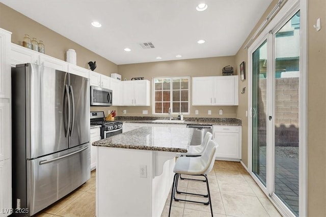 9869 Lime Tree St, Las Vegas, NV 89178 - kitchen with appliances with stainless steel finishes, a sink, white cabinetry, a center island, and stone counters
