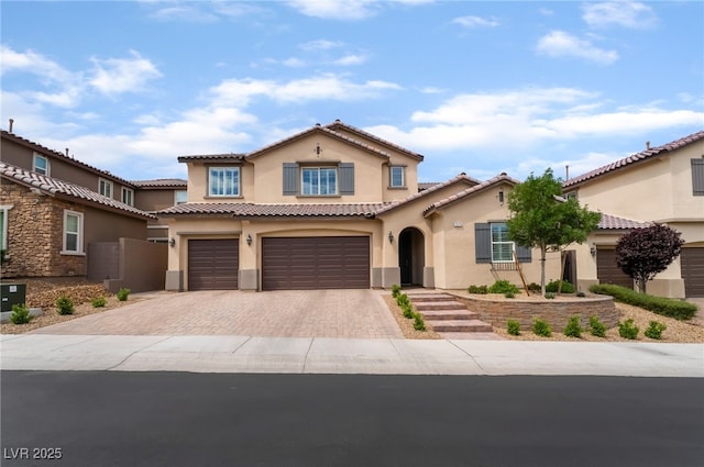 2575 Hazelburn Ave, Henderson, NV 89044 - mediterranean / spanish house featuring stucco siding, an attached garage, decorative driveway, and a tiled roof